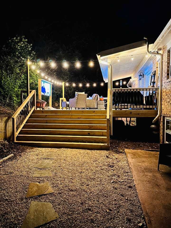 A wooden deck with stairs and lights on it is lit up at night.