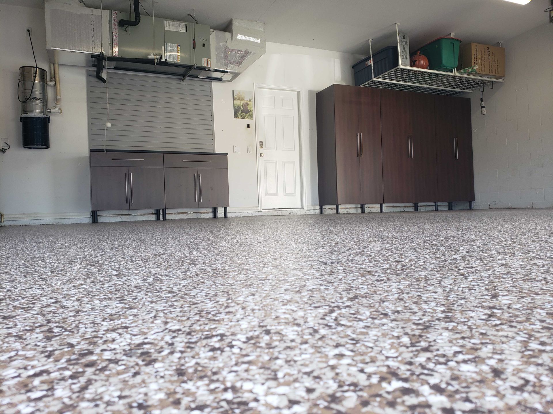 Garage interior with speckled floor, cabinets, and white door.