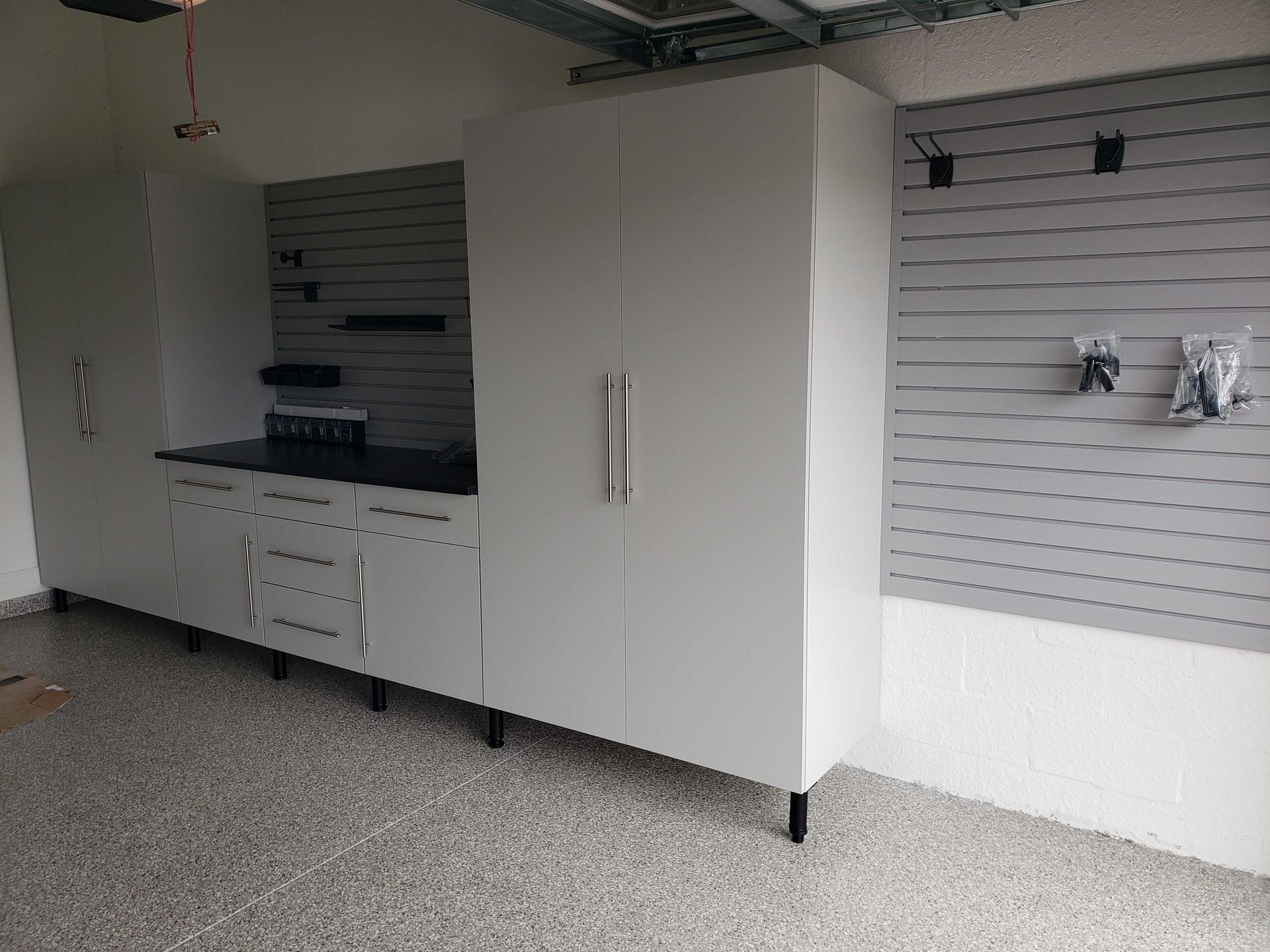 Gray garage storage cabinets and shelving against a gray and white speckled floor and walls.
