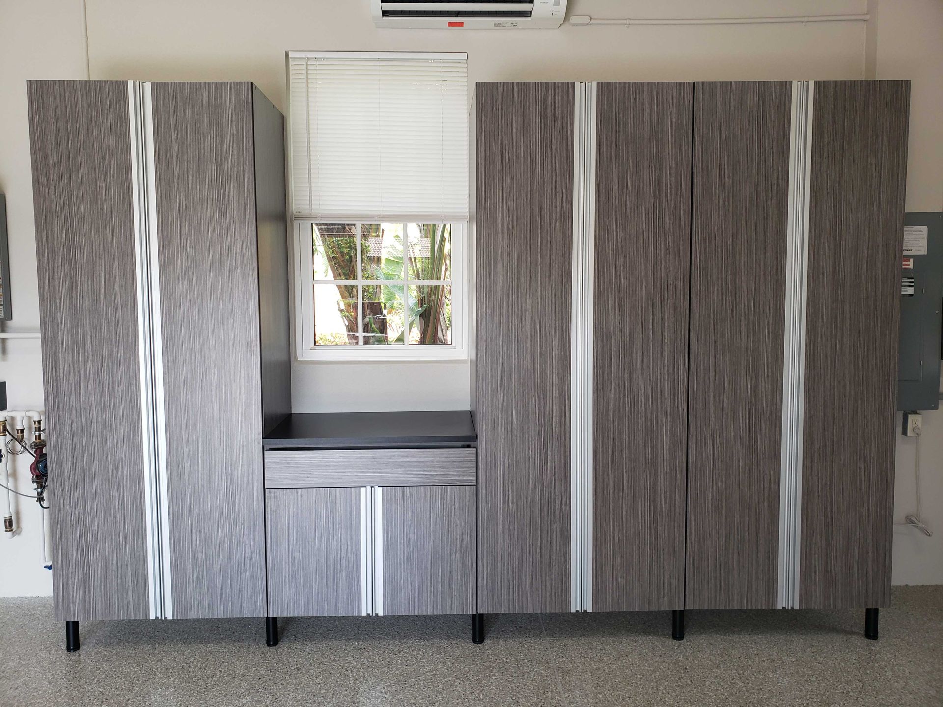 Gray and silver garage cabinets with a window in the middle.