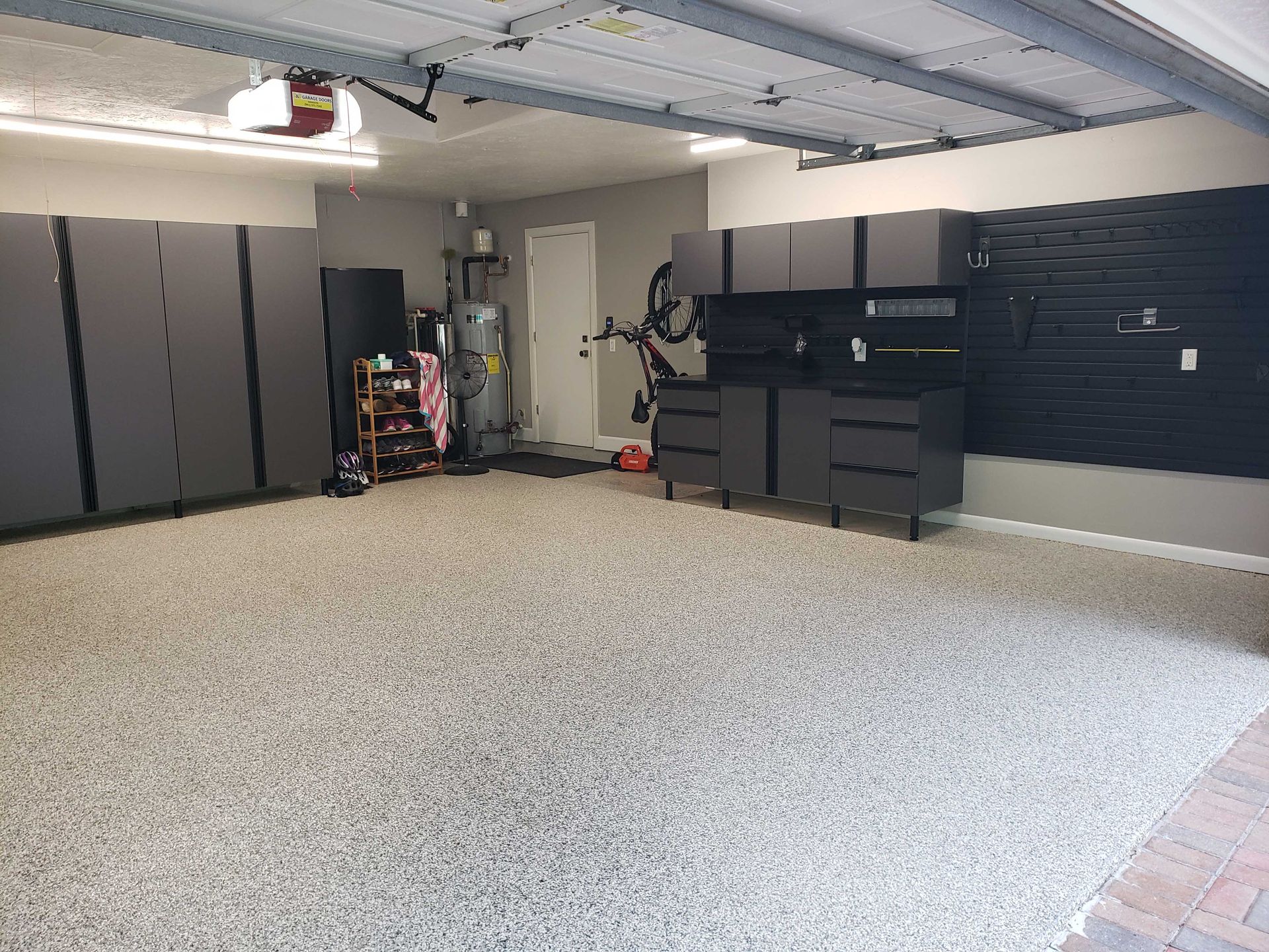 Gray epoxy garage floor with gray cabinets, shelving, and storage.