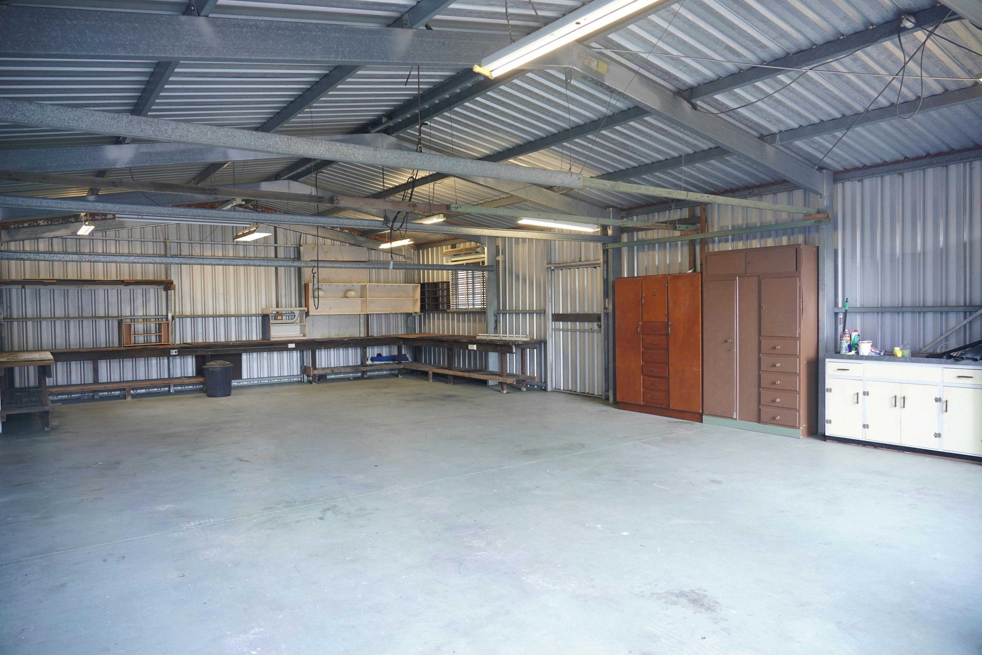 Empty workshop with a concrete floor, metal walls and ceiling, and work benches.