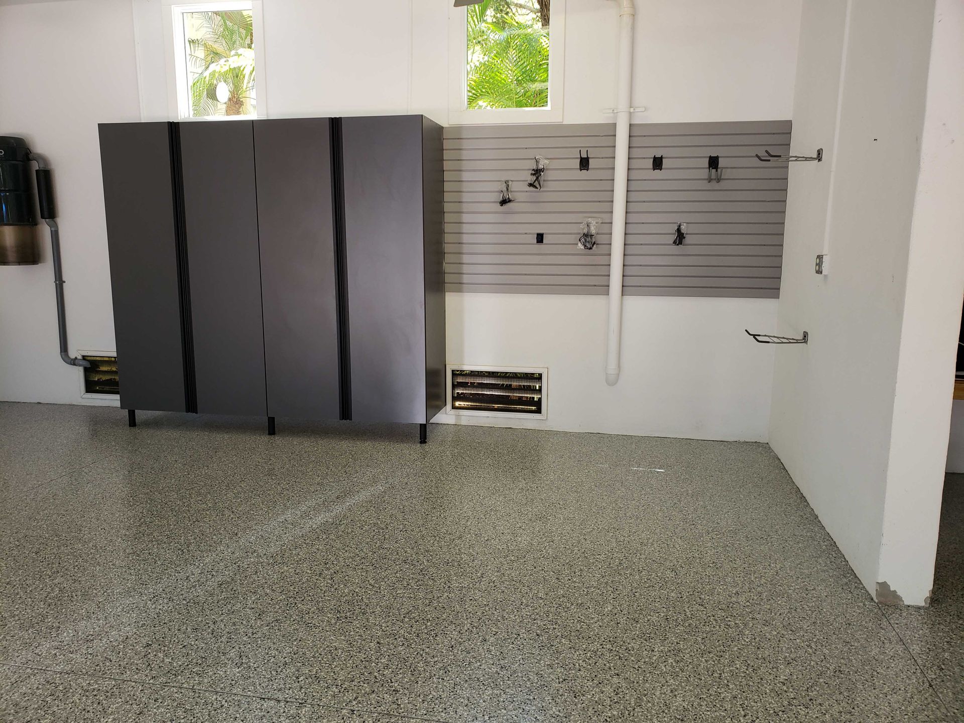 Garage interior: gray cabinets, pegboard, speckled floor, white walls.