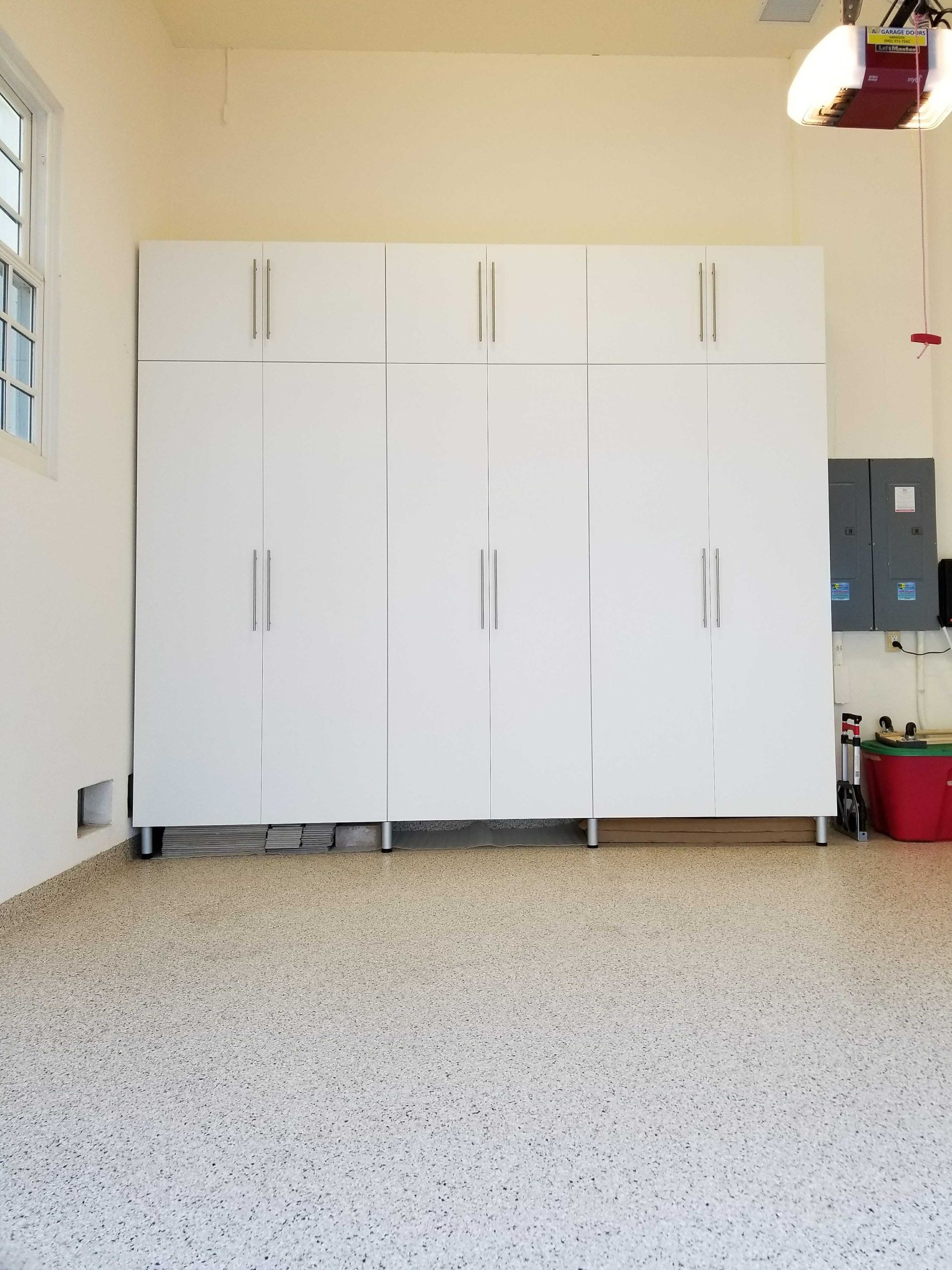 White garage storage cabinets against a beige wall, set on a speckled floor.