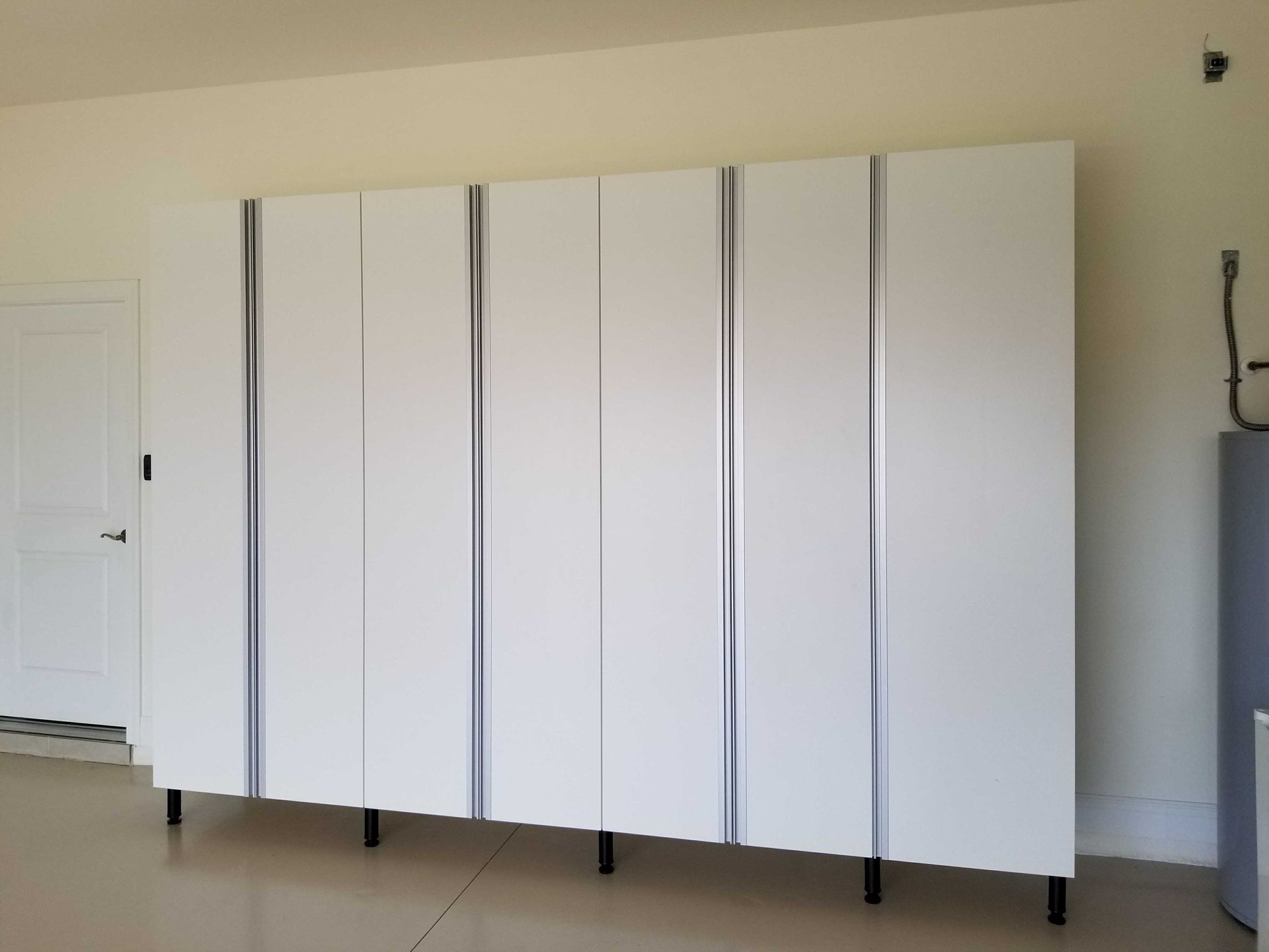 White garage storage cabinets with black legs against a light wall.