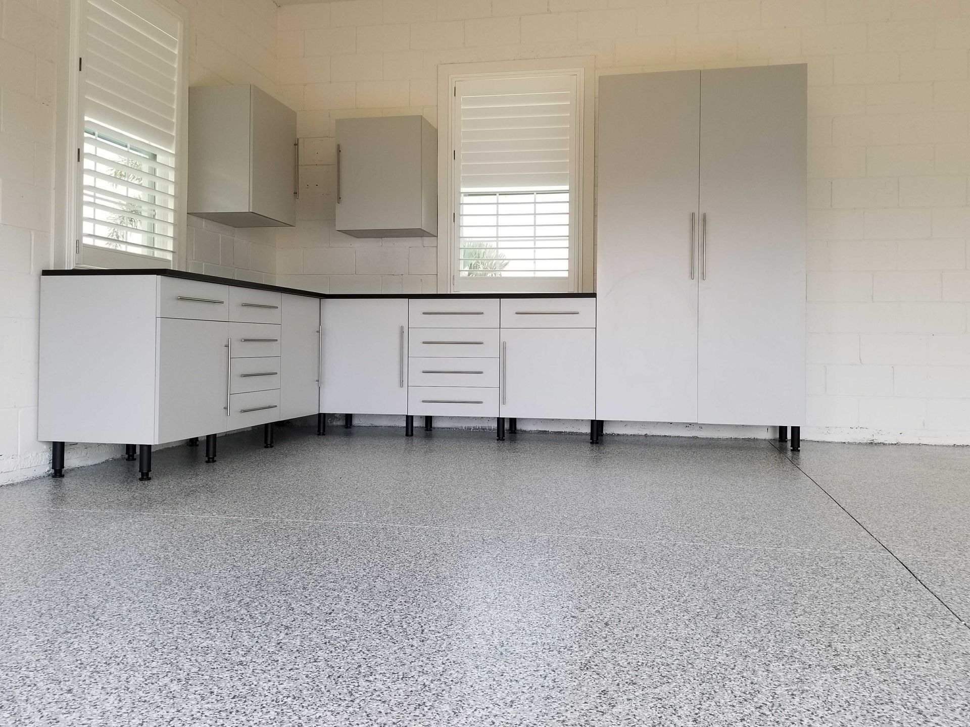 Gray and white garage with cabinets and a speckled epoxy floor.