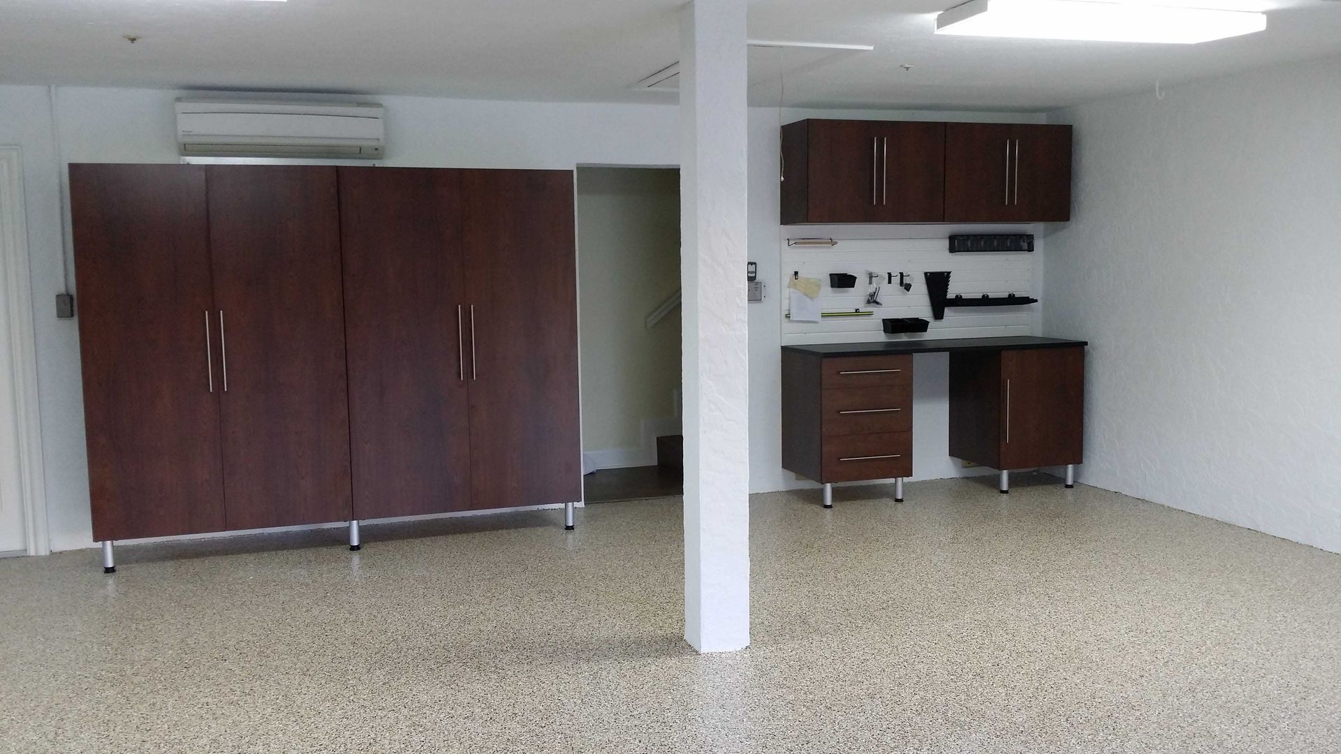 Garage with dark wood cabinets, work desk, and speckled floor.