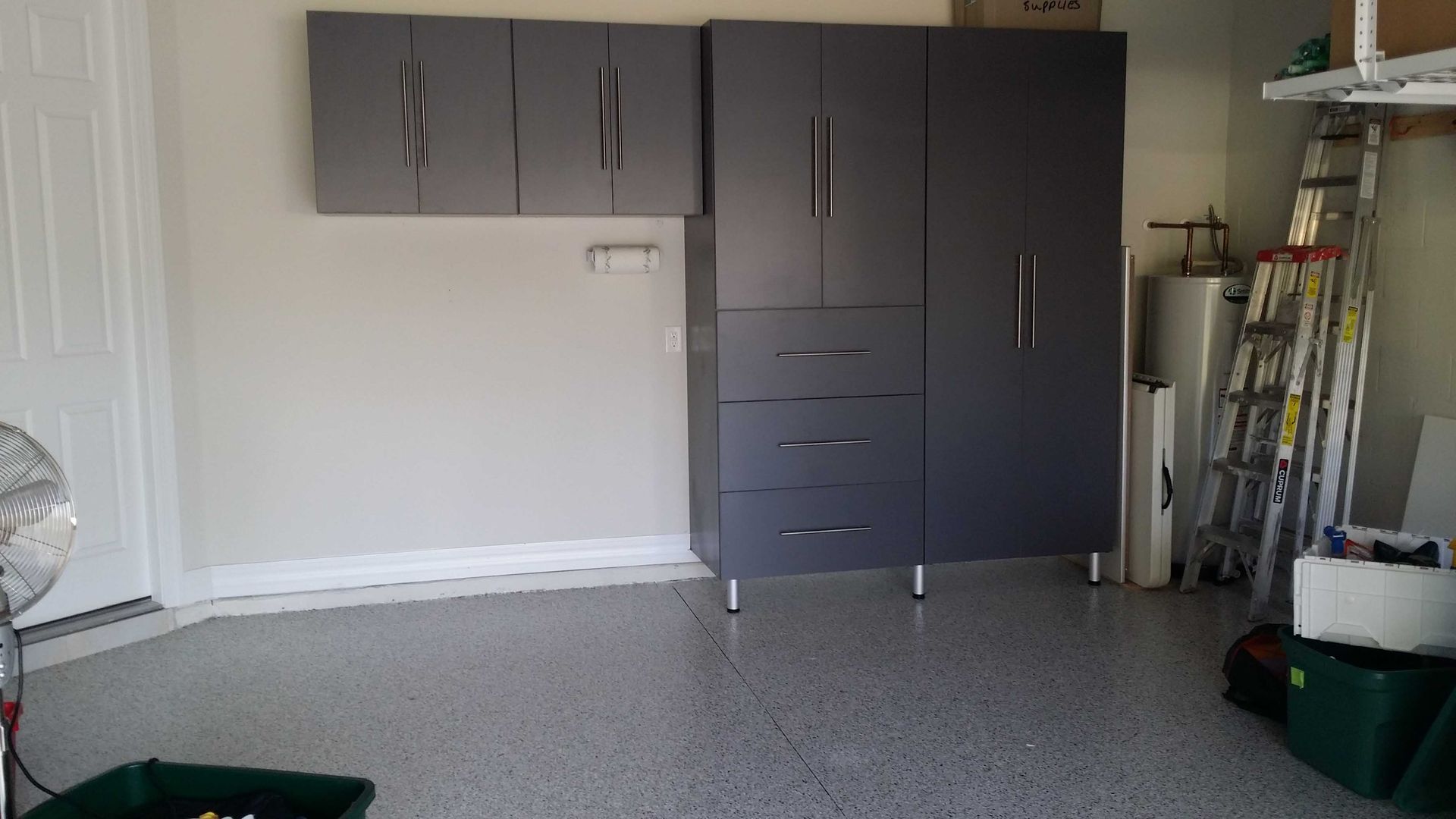 Gray garage cabinets against a light gray wall, with a speckled garage floor.