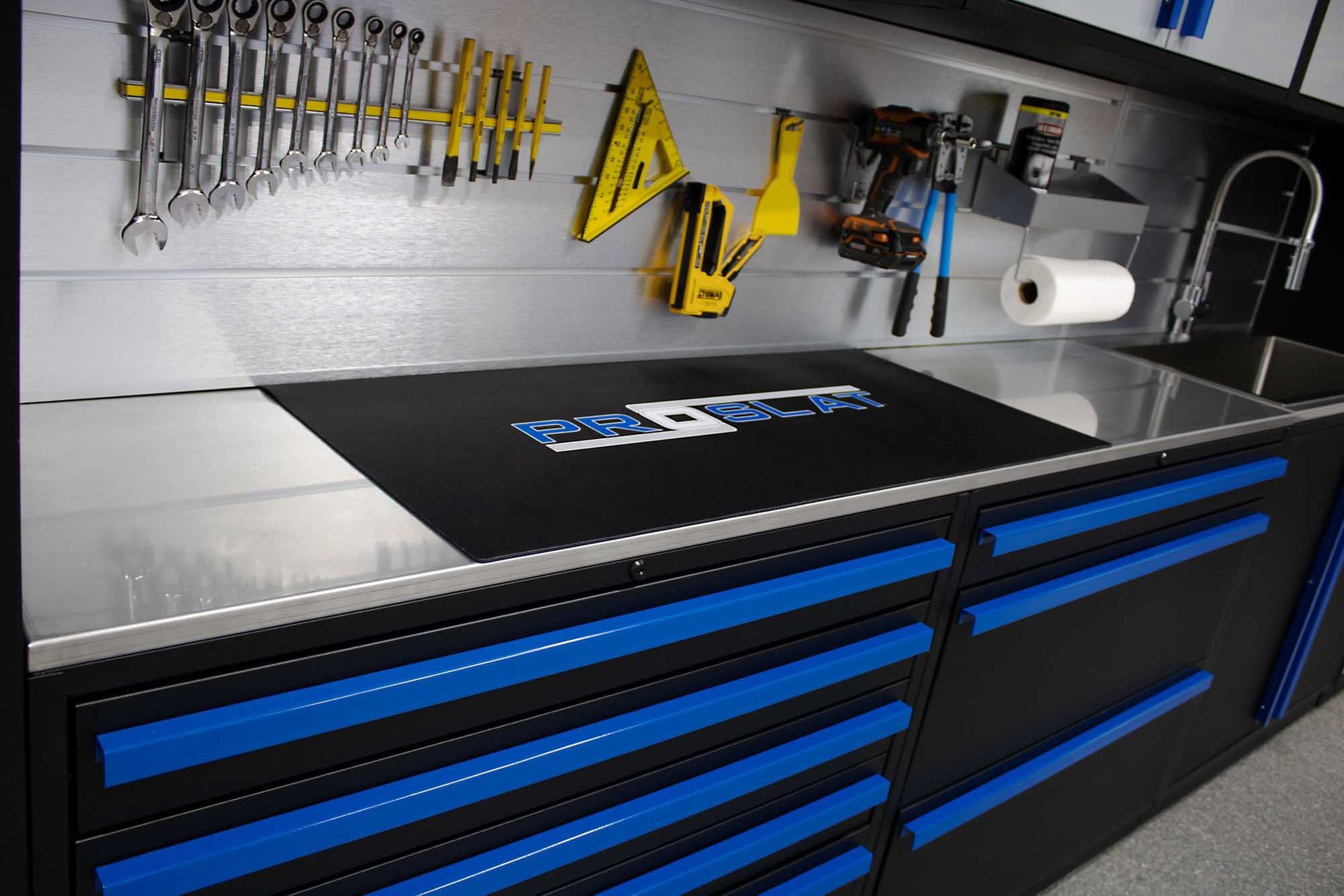 Garage workbench with tools, blue drawers, and a sink.