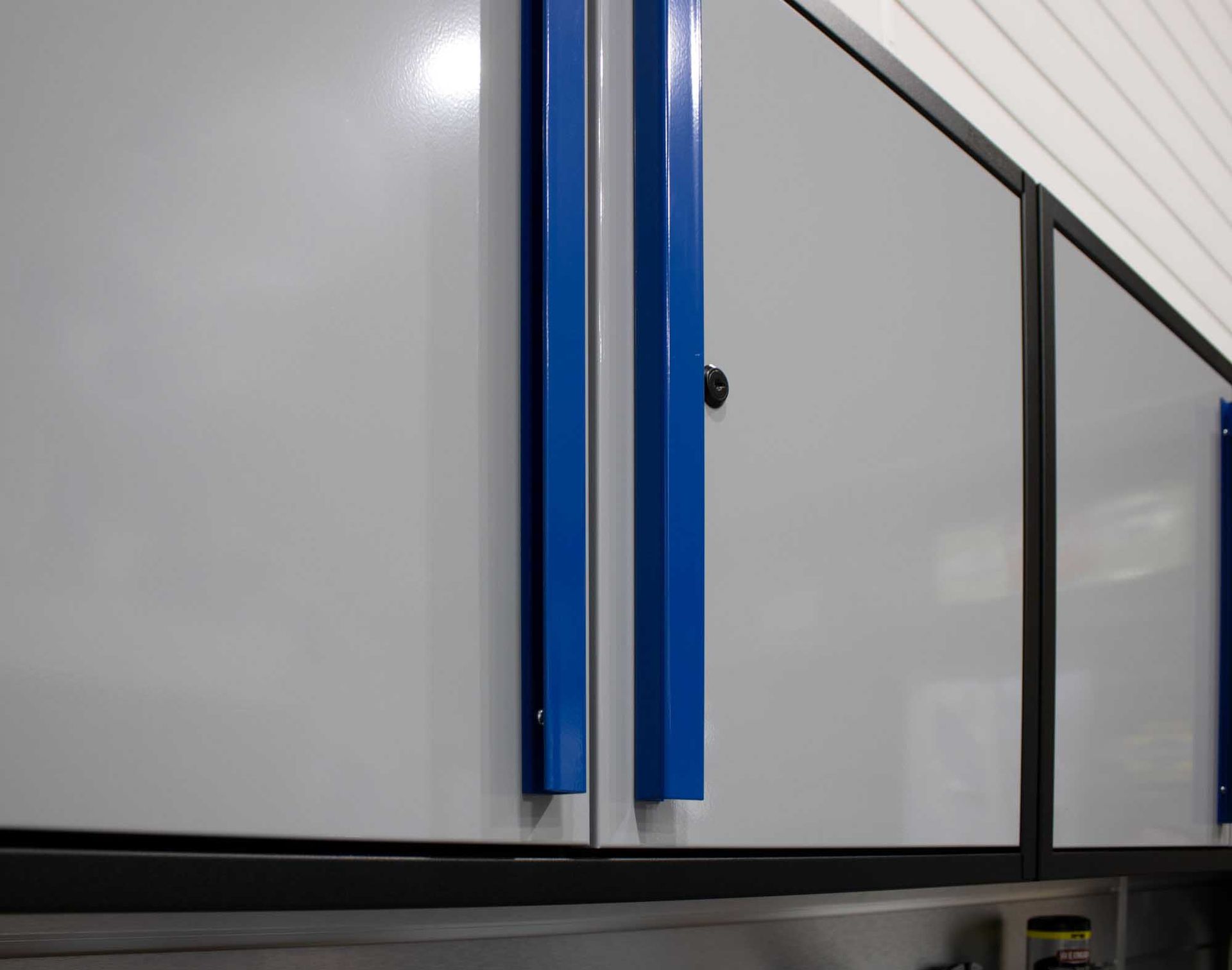 Gray cabinets with blue handles in a workshop.