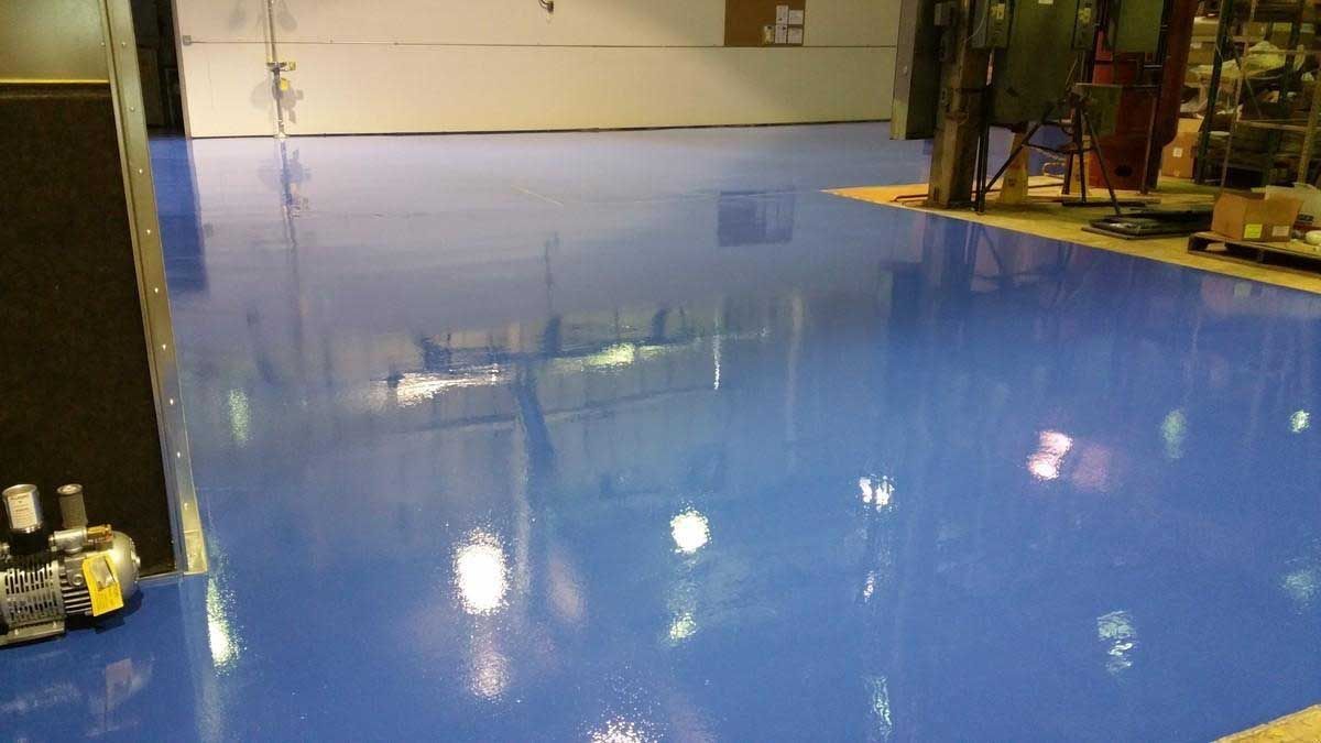Blue epoxy floor in a large, brightly lit industrial space.