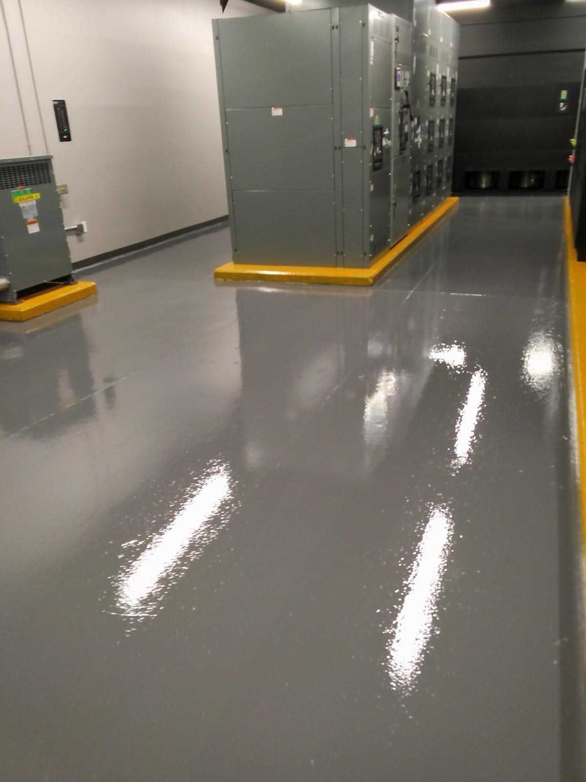 Grey and glossy industrial floor with machinery, edged with yellow safety borders.