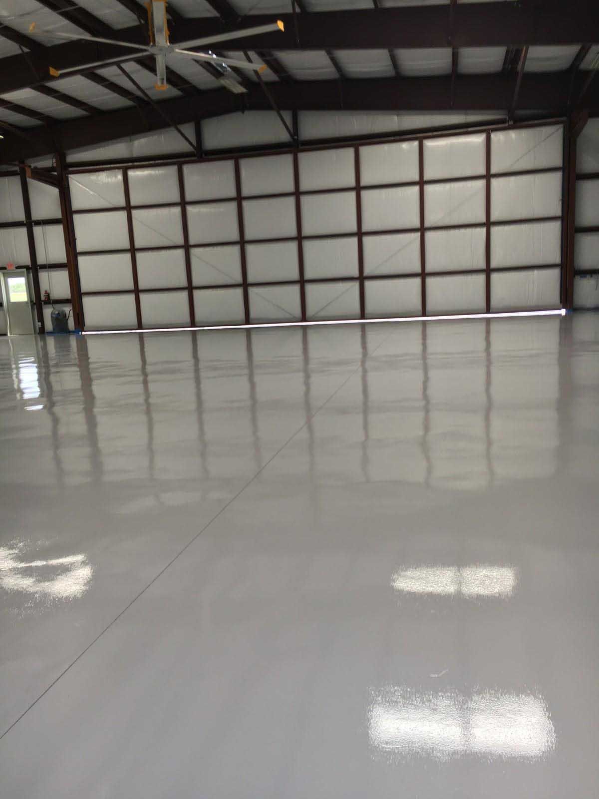 Shiny gray interior floor reflecting the walls of a large, empty industrial building.