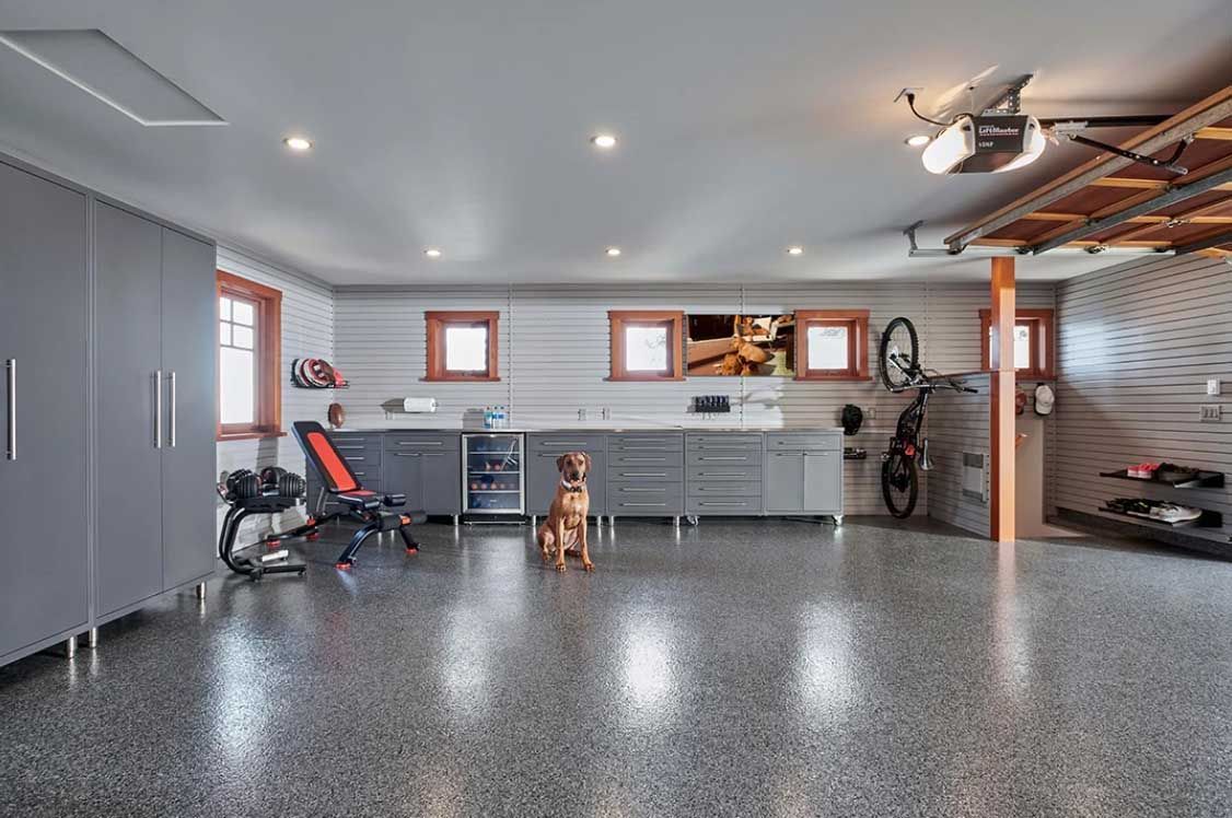 Spacious garage with cabinets, workout equipment, a dog, and a bicycle. Polished floor, grey walls.