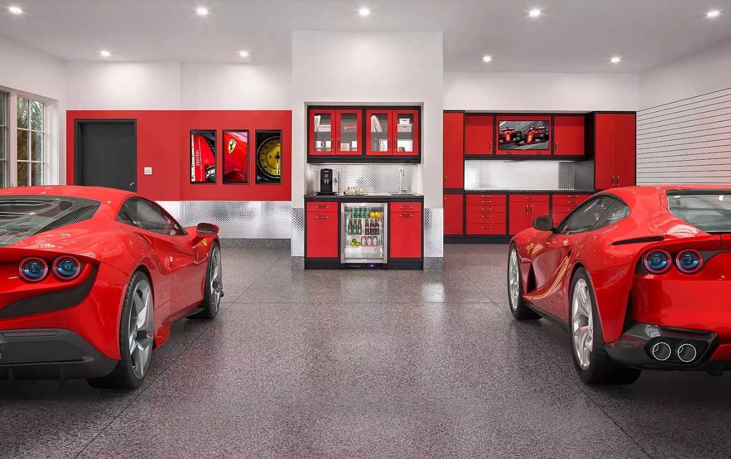 Two red sports cars parked in a garage with red cabinets and a small kitchen area.