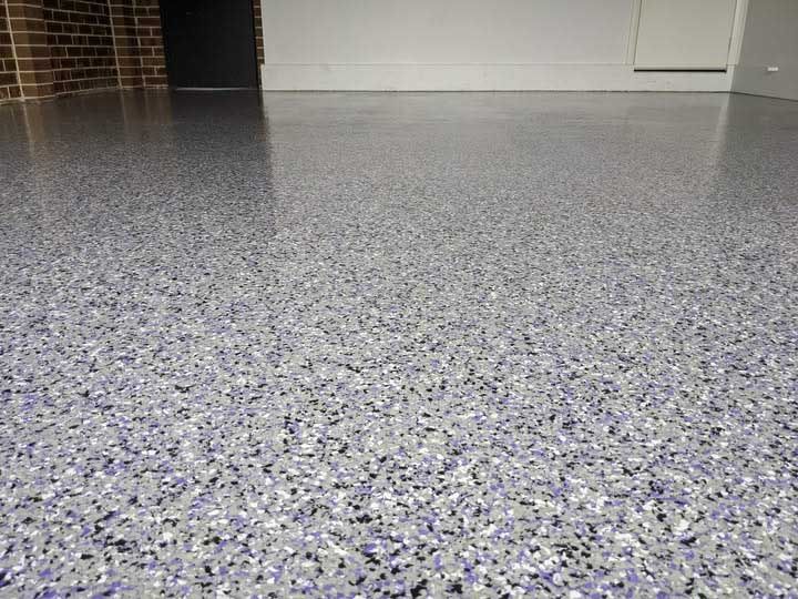 Gray epoxy garage floor with colorful flecks, reflecting light.