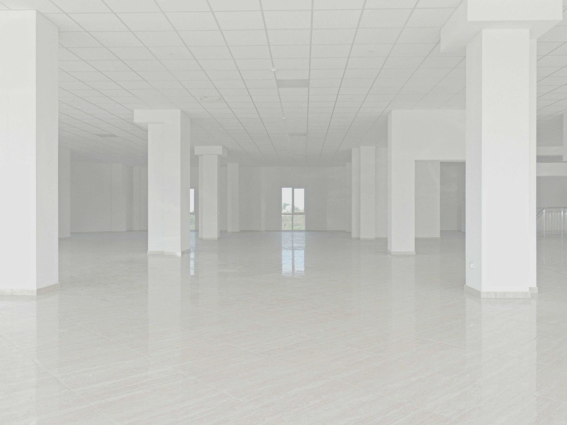 Empty, white interior space with pillars and reflective floor.