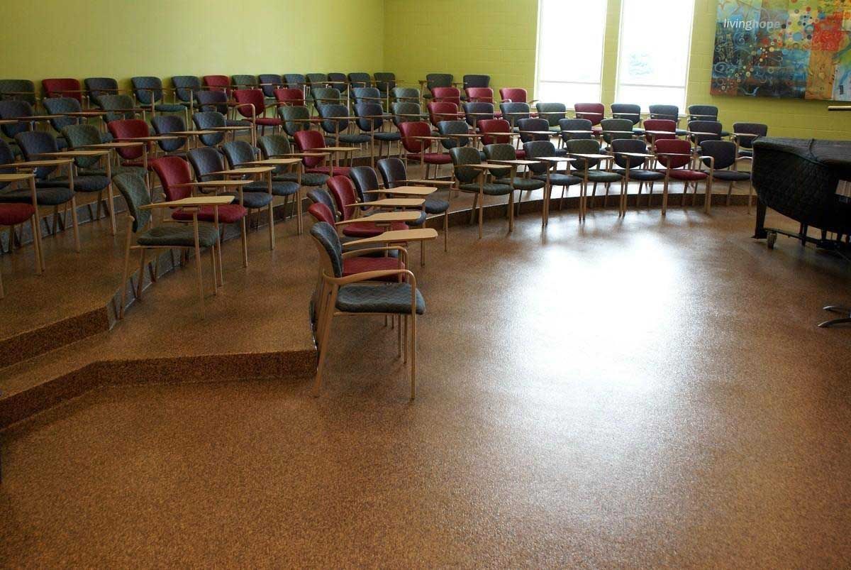 Auditorium with rows of seats on tiered levels, dark chairs, and a bright floor.