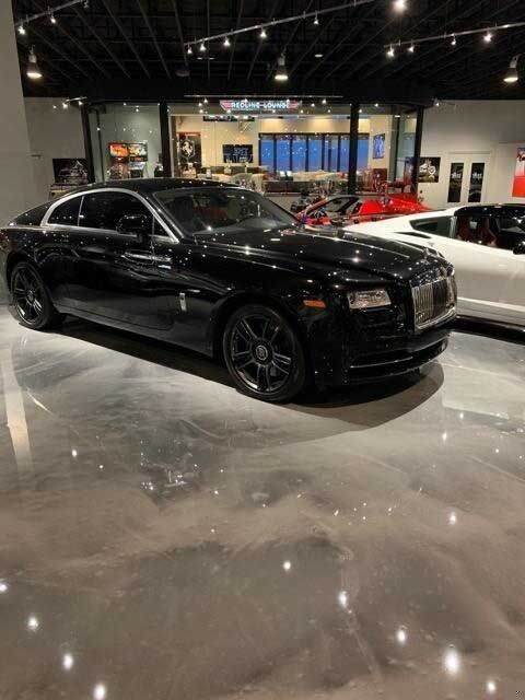Black Rolls Royce coupe in a showroom with shiny flooring.