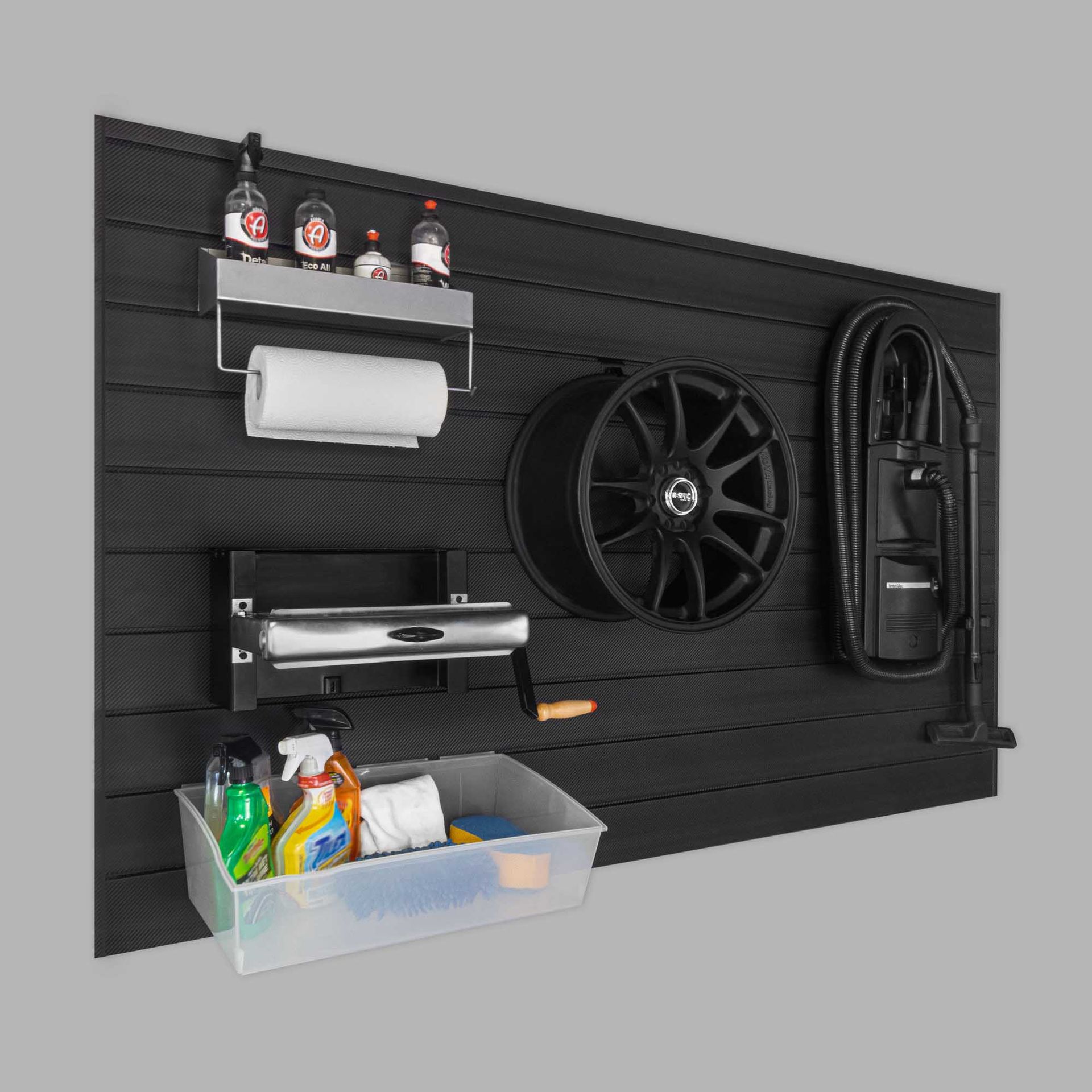 Black garage wall with storage: a wheel, vacuum, shelves with bottles, and a cleaning supply bin.