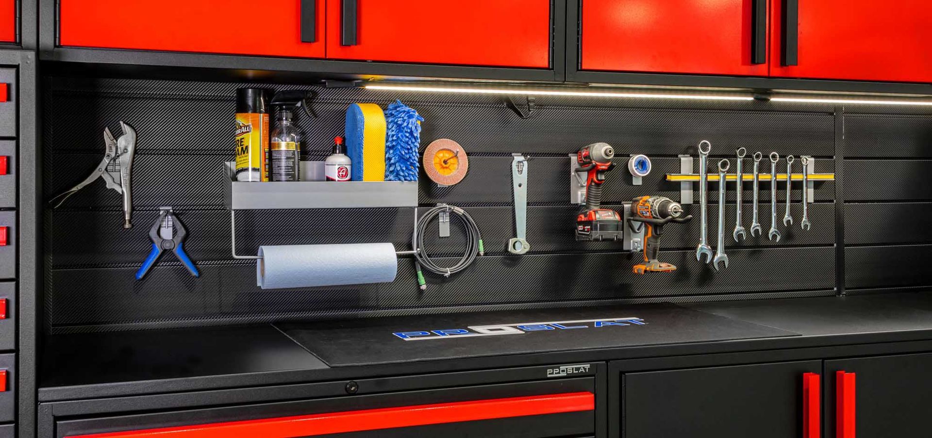 Garage workspace with black and red cabinets, tools on a pegboard wall.