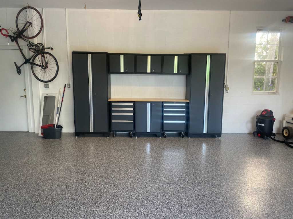 Garage with a workbench, cabinets, and a bicycle on the wall. Epoxy floor.