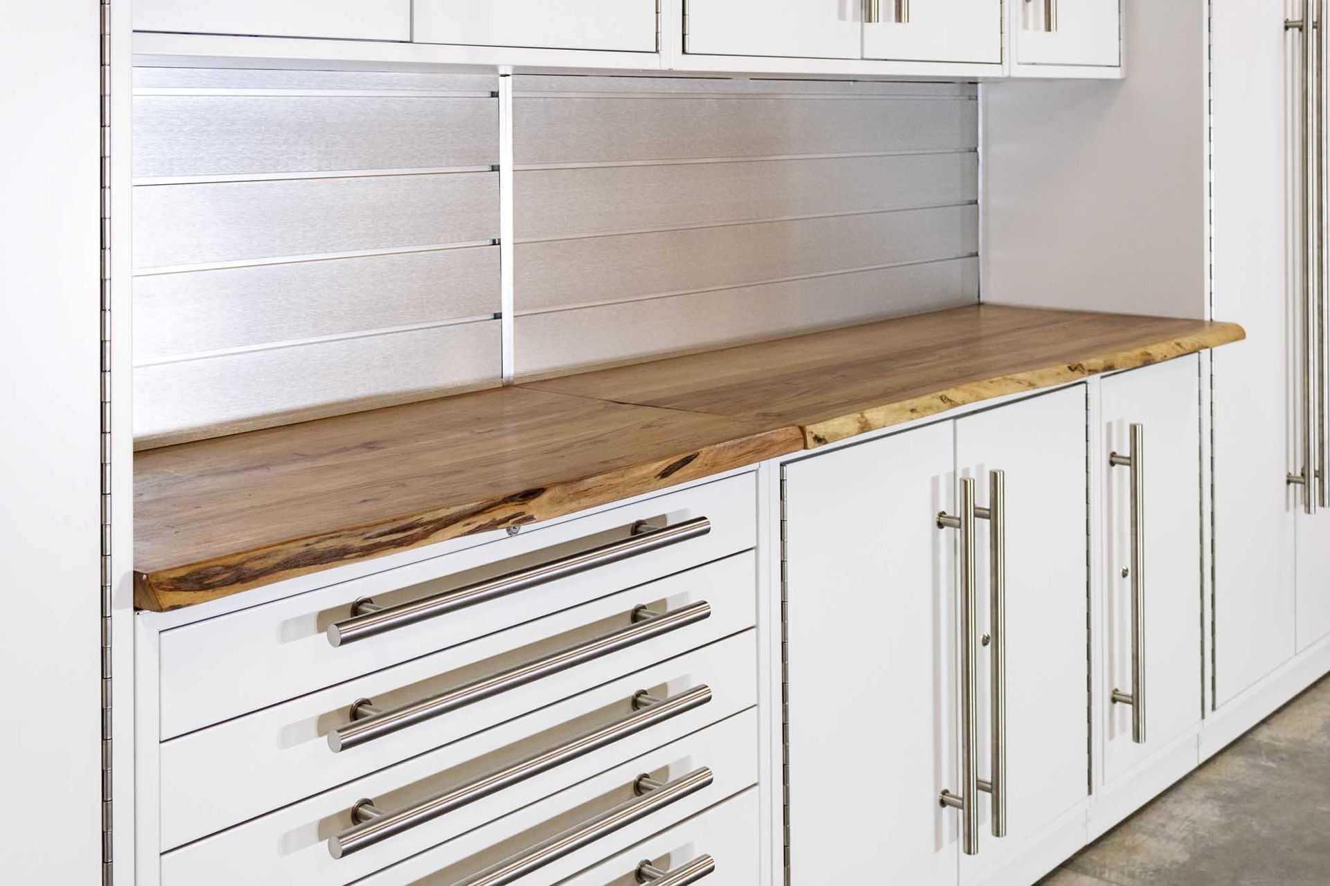 White storage cabinets with a wood countertop and stainless steel hardware.