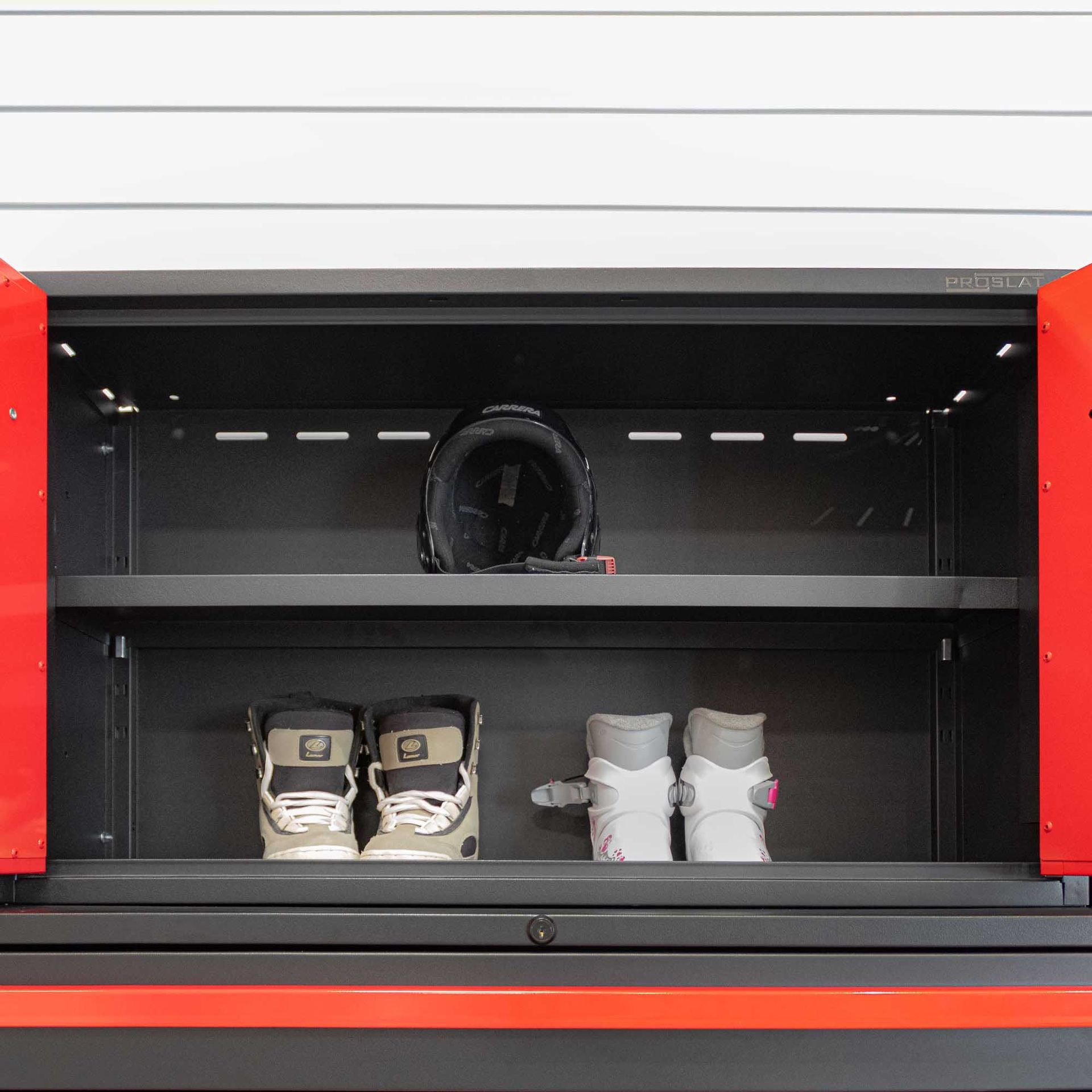 Open black and red cabinet with helmet and boots inside.