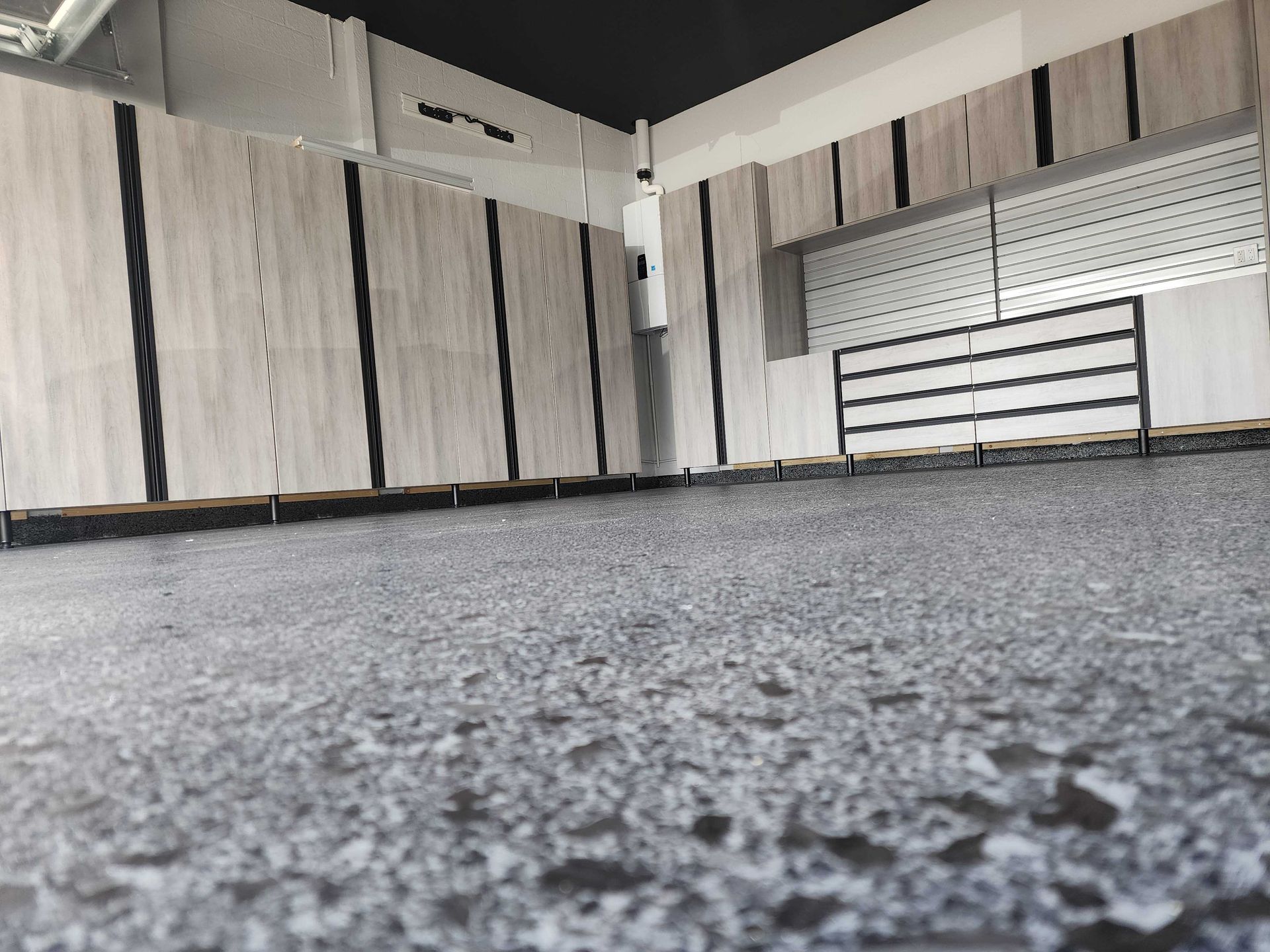 Grey floor, light gray wall panels with vertical black stripes, a display area, and a dark ceiling.