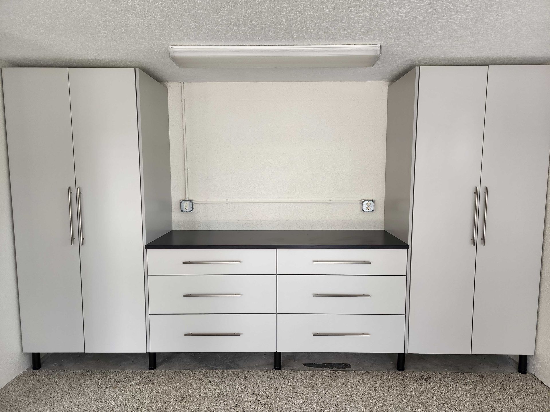 Garage storage system with gray cabinets and drawers, black countertop.