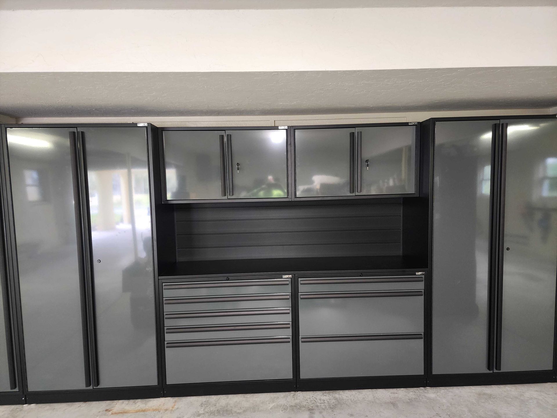 Garage cabinets, gray with black trim, organized along the wall.