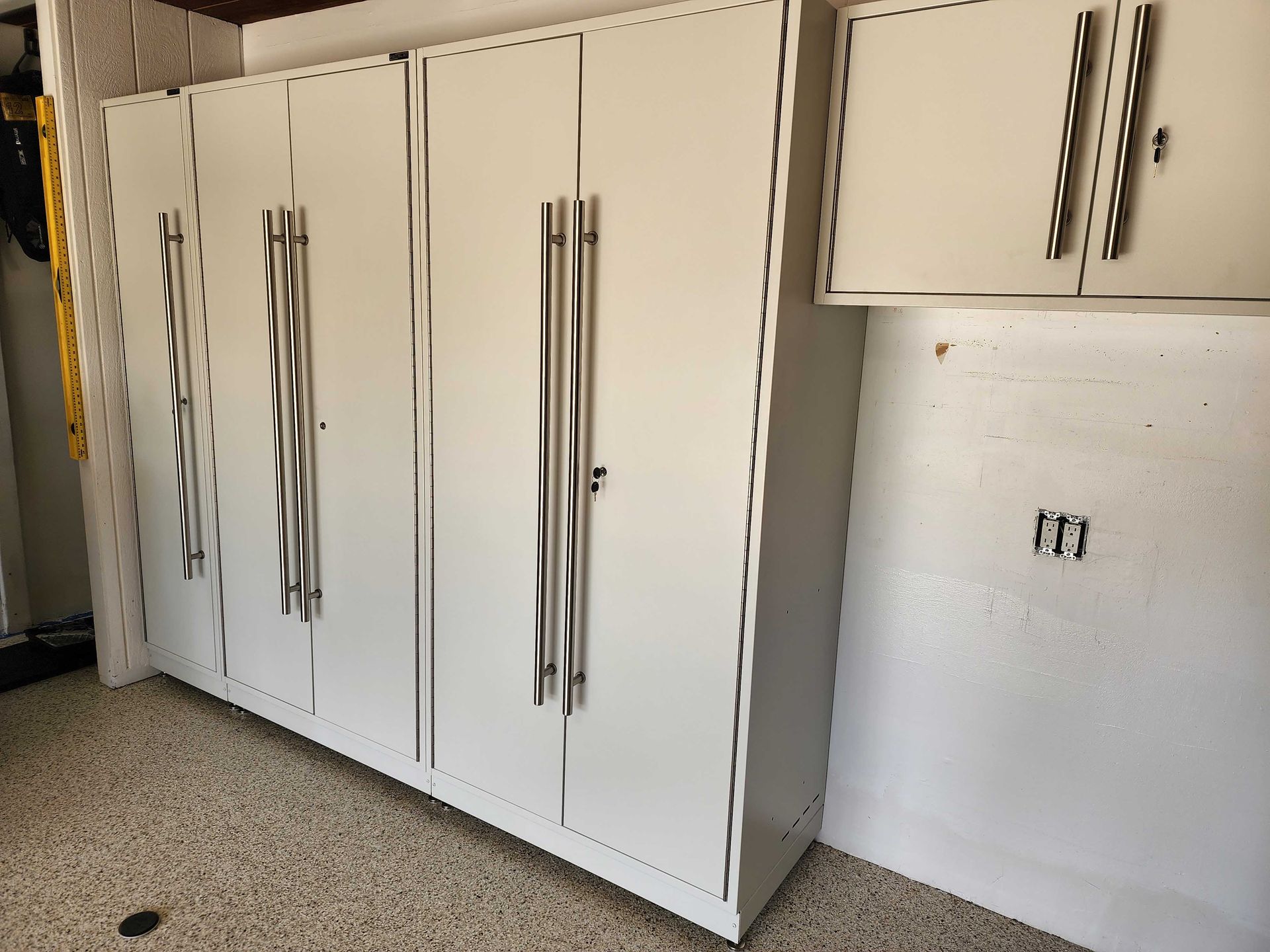 White storage cabinets with wavy metal handles in a garage.