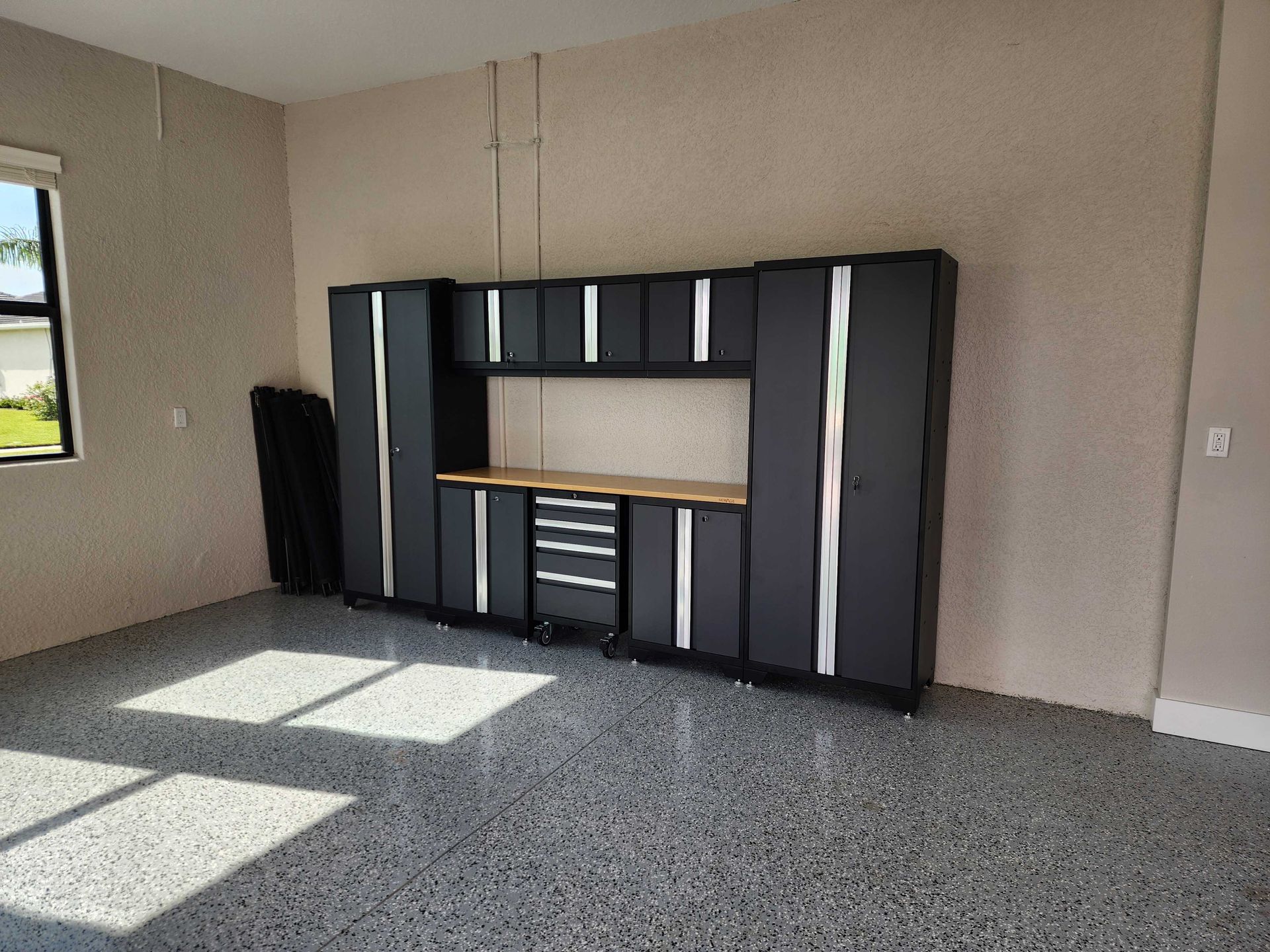 Garage with dark gray storage cabinets and a speckled floor.