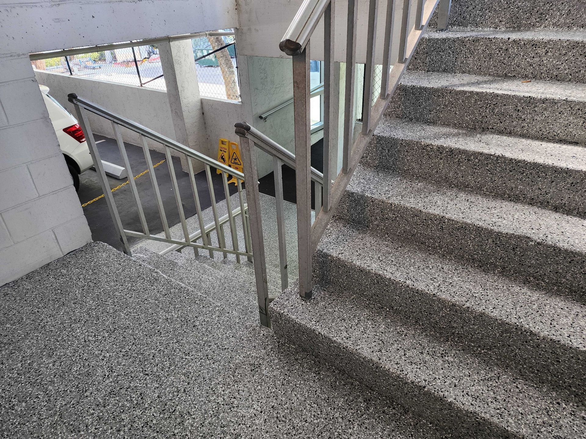 Staircase with grey speckled steps and metal railings in an industrial setting.
