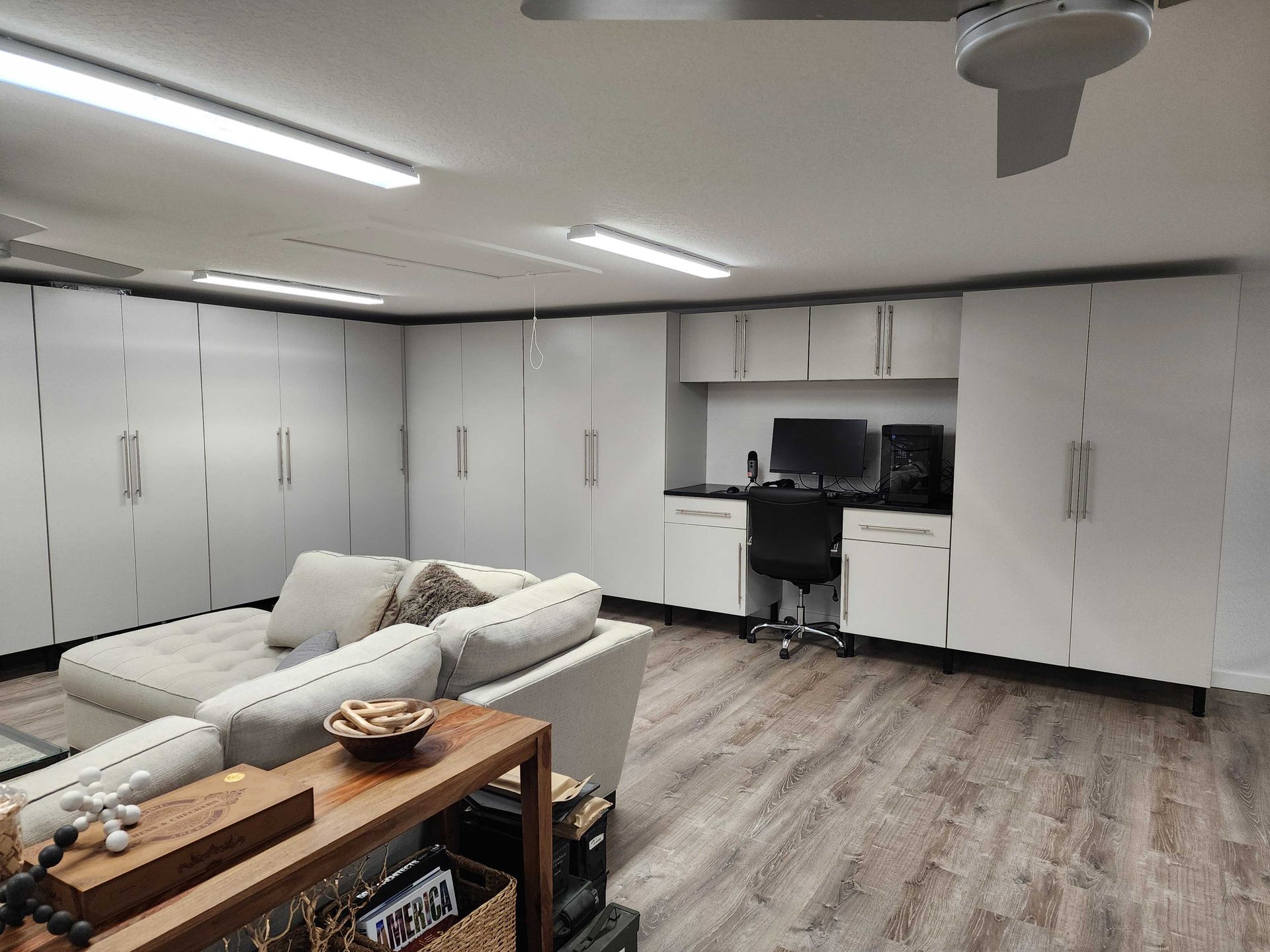 Living space with white storage cabinets, a desk, sofa, and ceiling fan.
