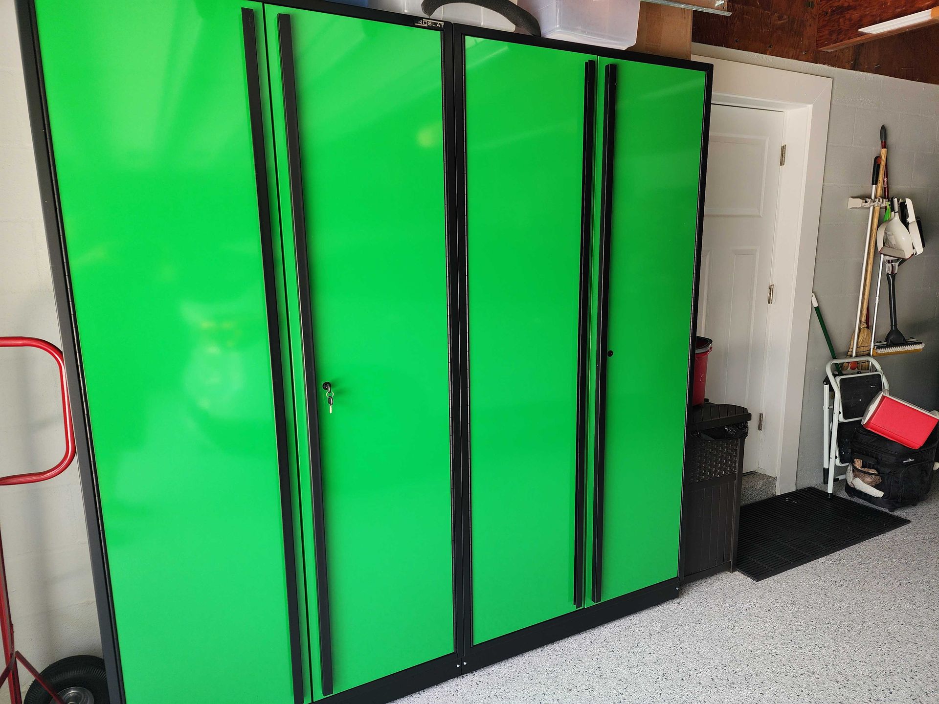Green storage cabinets with black trim in a garage.