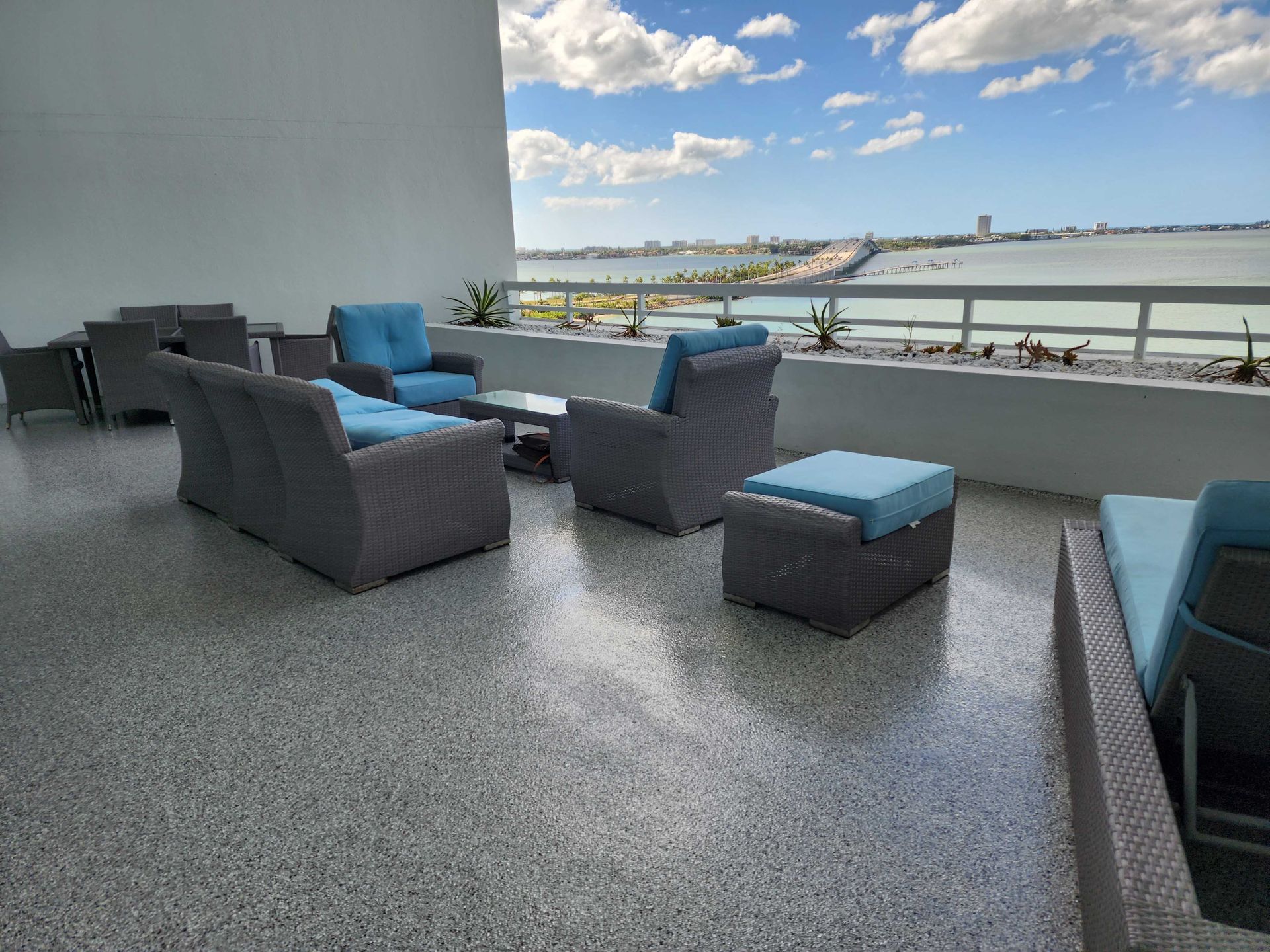 Outdoor patio with gray wicker furniture, blue cushions, and water view.