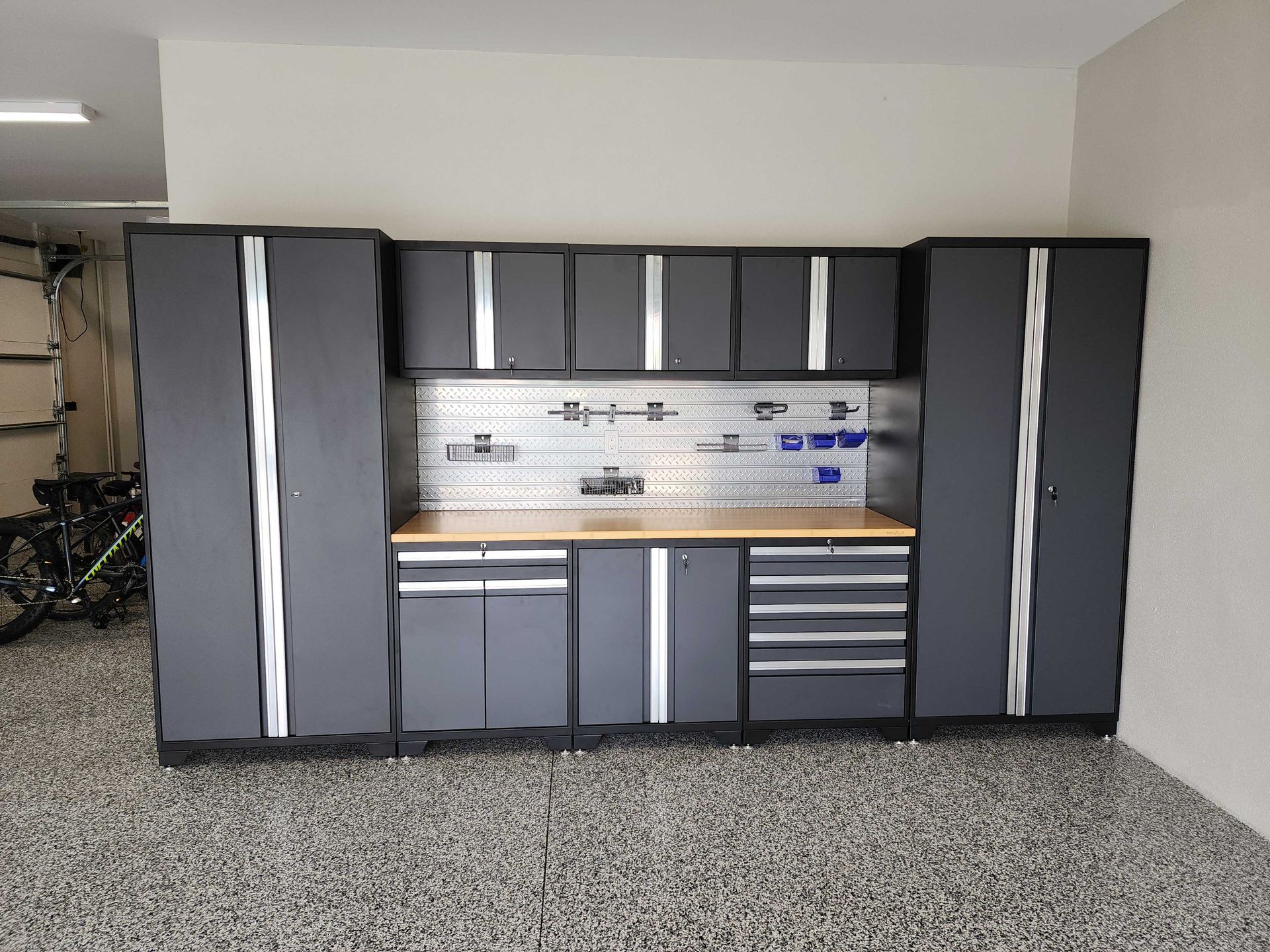 Garage workshop with gray cabinets, pegboard, and a workbench.