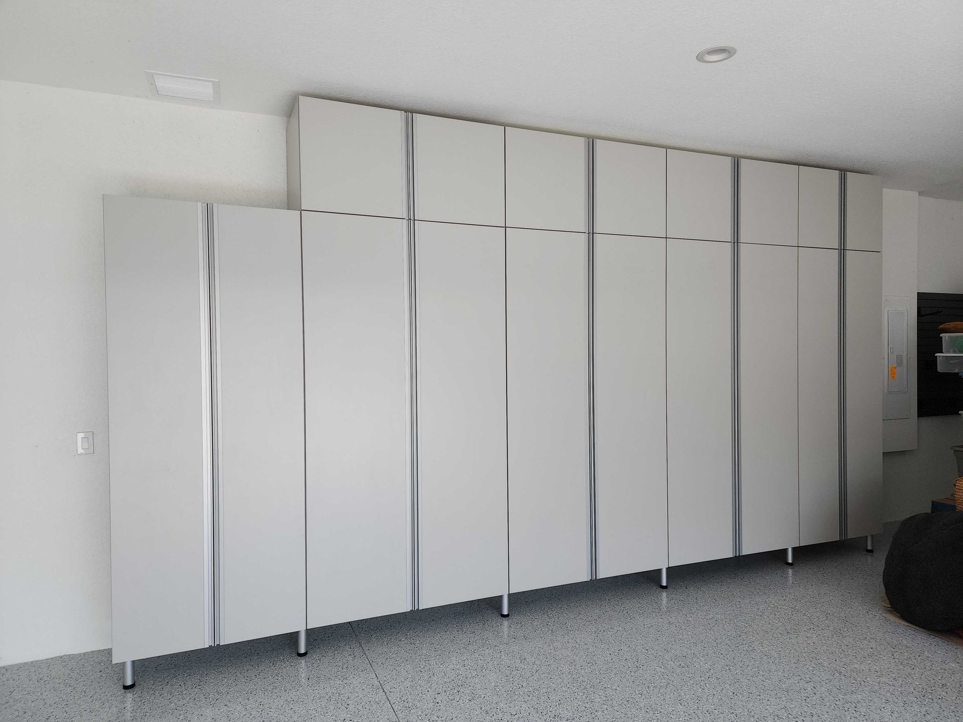 Large white cabinets with silver handles against a light-colored wall and floor.
