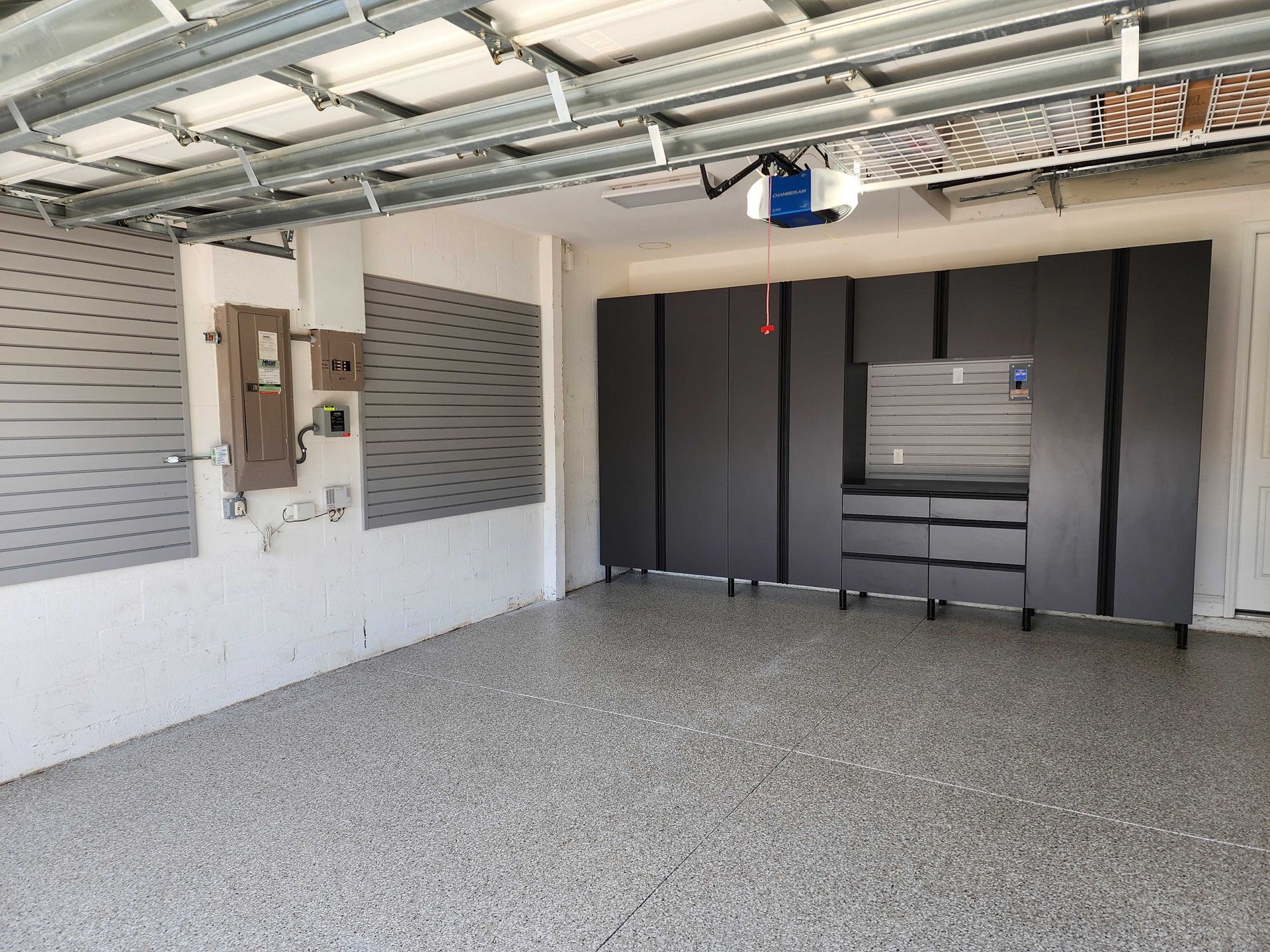 Gray garage with cabinets, speckled flooring, and a garage door opener.
