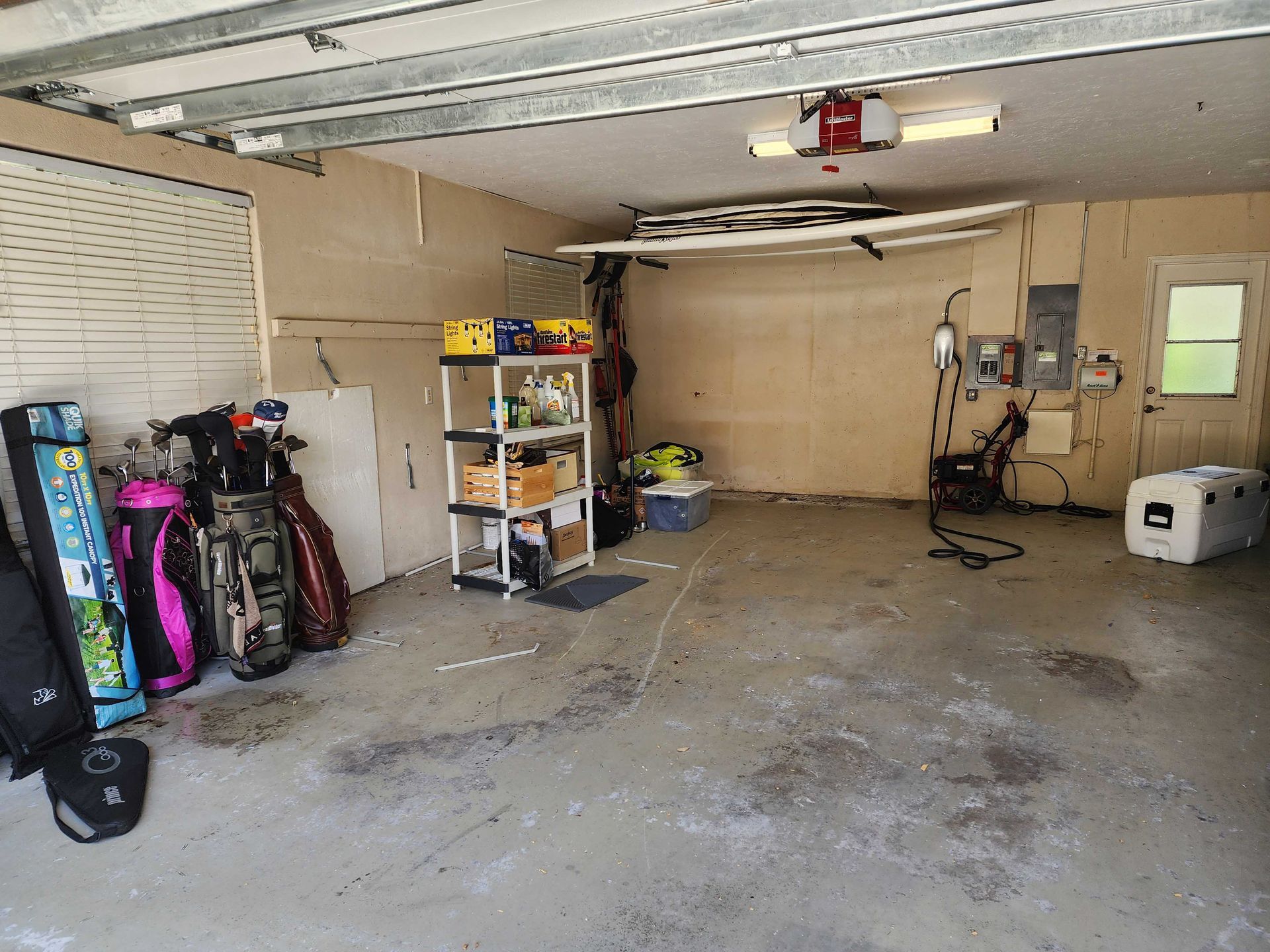 Garage interior with golf bags, shelving unit with boxes, and electrical panels on the wall.