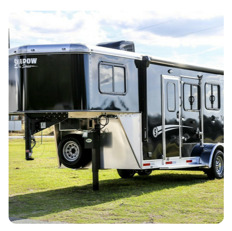 A black and silver trailer is parked in a grassy field.