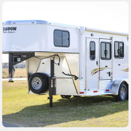 A shadow horse trailer is parked in the grass