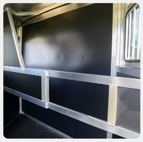 The inside of a horse trailer with black walls and a window