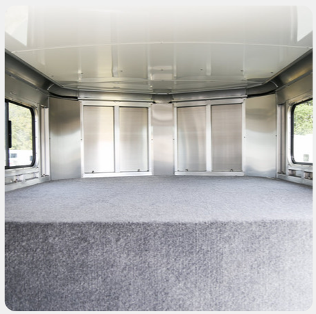 An empty room with a carpeted floor and stainless steel walls
