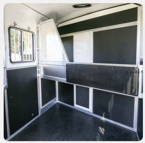 The inside of a horse trailer with black and white walls