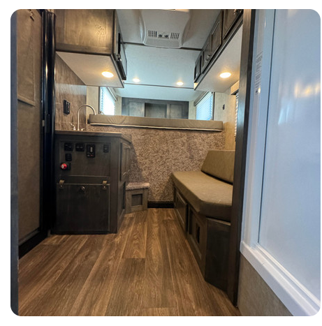 The inside of a rv with a couch and a sink.