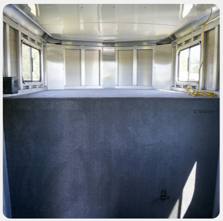 The inside of a trailer with a gray carpeted floor