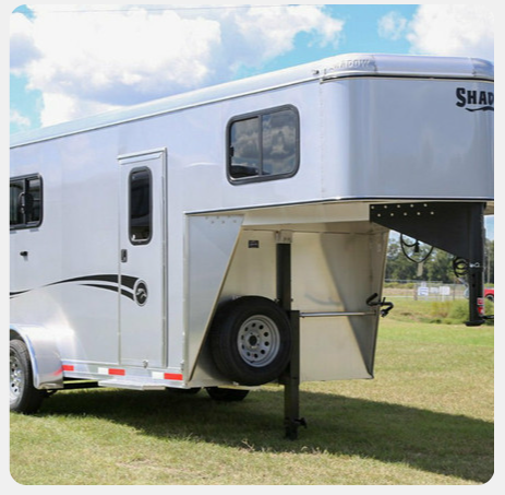 A horse trailer is parked in a grassy field