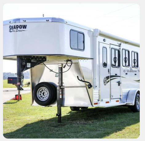 A shadow horse trailer is parked in the grass